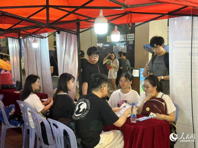 夜市招聘会上，求职大学生正在与用人单位进行交流。人民网记者 张萌摄