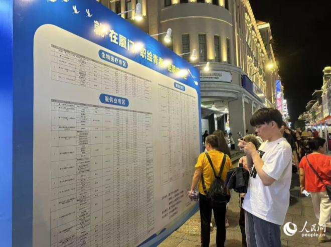 活动现场，求职者正在记录招聘信息。人民网记者 张萌摄