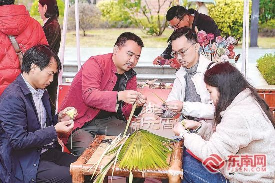 非遗传承人指导游客用棕榈叶编织元宵主题的小灯笼和花朵。